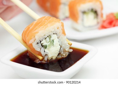 Sushi Roll In Chopsticks In Soy Sauce, Closeup