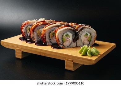 rollo de sushi con anguila y gambas en tablero de madera