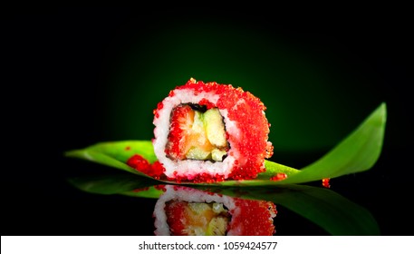 Sushi roll isolated on black background. Sushi japanese food in restaurant. Piece of California Sushi roll set with salmon, vegetables, flying fish roe and caviar closeup. Japan restaurant menu. 