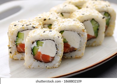 Sushi roll with salmon, philadelphia cheese and sesame on plate close up