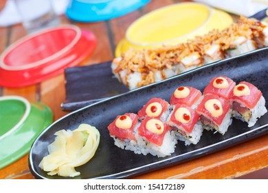 Sushi Roll With Tuna, Avocado, Spicy Mayo, Ginger, Wasabi Surrounded By Colorful Plating.