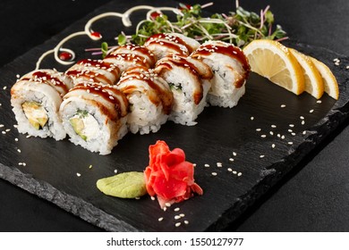 Sushi Rolls with cucumber, avocado, eel and Cream Cheese inside on black slate isolated. Philadelphia unagi roll sushi with shrimp. Sushi menu. Horizontal photo.