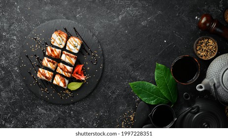 Sushi Rolls With Eel, Cucumber And Cheese On A Black Stone Plate. Japanese Cuisine. Top View.