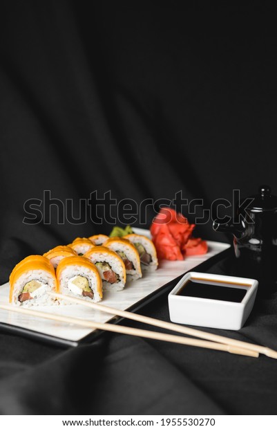 Sushi Rolls with\
processed cheese cheddar, american cheese, avocado, tuna and cream\
cheese inside on white slate on black background. Philadelphia roll\
sushi. Sushi menu.