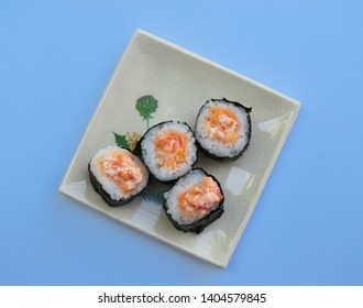 Sushi rolls are in a rectangular dish on a blue background.