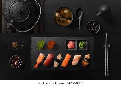 Sushi Rolls, Sashimi Set, Miso Soup And Teapot, On Dark Wooden Table, Japanese Food, Top View.