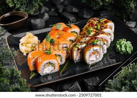 Sushi rolls set served on black stone plate with wasabi and ginger