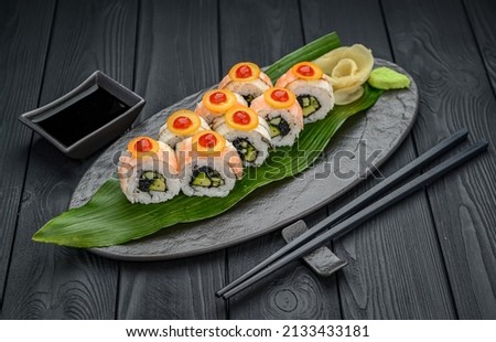 Sushi rolls with shrimp, black tobiko caviar and spicy sauce. Traditional delicious fresh sushi roll set on a black background. Sushi menu. Japanese kitchen, restaurant. Asian food