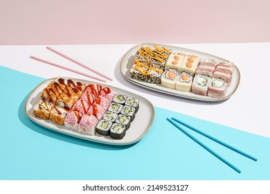 Sushi set on ceramic dishware with coloured chopsticks. Trendy set of maki sushi in minimal style. Modern japanese menu concept. Maki sushi assorted on coloured background - Shutterstock ID 2149523127