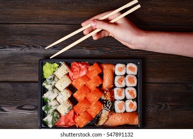 Sushi Set On A Wooden Background, Sushi Sticks In Their Hands