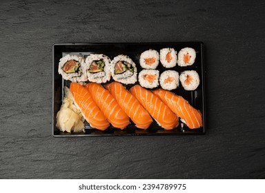 Sushi Set in Plastic Container, Take Away Salmon Susi Rolls Lunch Box, Nori Maki, Nigiri Sushi Roll on Black Stone Background - Powered by Shutterstock