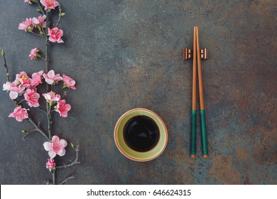 Sushi Set. Small bowl of soy sauce, chopsticks and cherry blossoms, served on stone background. Top view, blank space  - Powered by Shutterstock