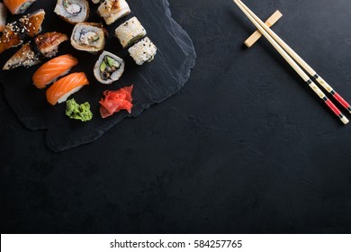 Sushi set with wasabi and ginger on black stone tray on black table. Top view.