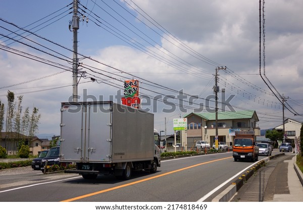 Susono, Japan - May 2014:\
View of main road in small industrial city with car and truck and\
electricity network cable post with building and clouds in blue sky\
background.