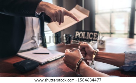 suspect with handcuffs being interviewed in interrogation room by Police officer, Criminal law concept