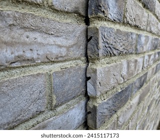 suspended brick-shaped tiles are anchored to the metal structure in a notch. the joints are filled with cement mortar. side view of the house wall