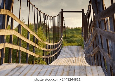 Suspended bridge with wooden fences, footpath from planks, close-up. Abstract lines go into perspective. Symmetric abstract objects in sunset light - Powered by Shutterstock