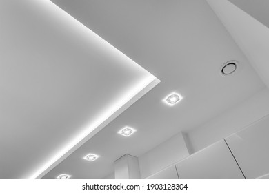 suspended ceiling with halogen spots lamps and drywall construction in empty room in apartment or house. Stretch ceiling white and complex shape. - Shutterstock ID 1903128304