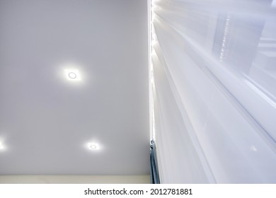 suspended ceiling with halogen spots lamps and drywall construction in empty room in apartment or house. Stretch ceiling white and complex shape.