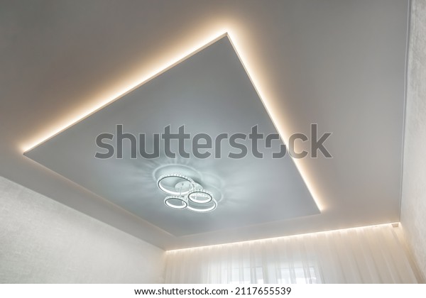 suspended ceiling with halogen spots lamps and\
drywall construction in empty room in apartment or house. Stretch\
ceiling white and complex\
shape.