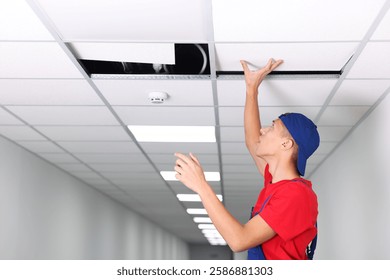 Suspended ceiling installation. Builder working with PVC tile indoors