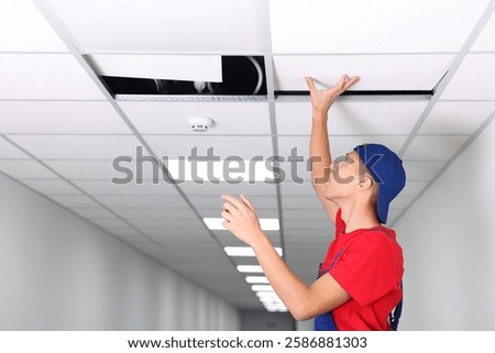 Suspended ceiling installation. Builder working with PVC tile indoors