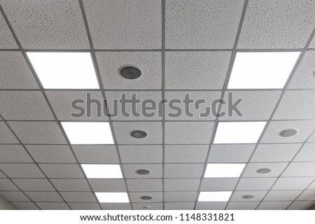 Suspended ceiling with LED square lamps and round speakers in the conference room.