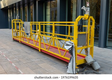 Suspended construction craddle after glazing the facade of a commercial object stands on the ground. Engineering urban background