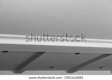 Suspended and grid ceiling with LED spots lamps and drywall construction in empty room in house interior. Stretch ceiling white and complex shape.