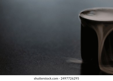 Suspended in a moment of tranquility, a petite black coffee cup releases wisps of ethereal dry-ice vapor. - Powered by Shutterstock