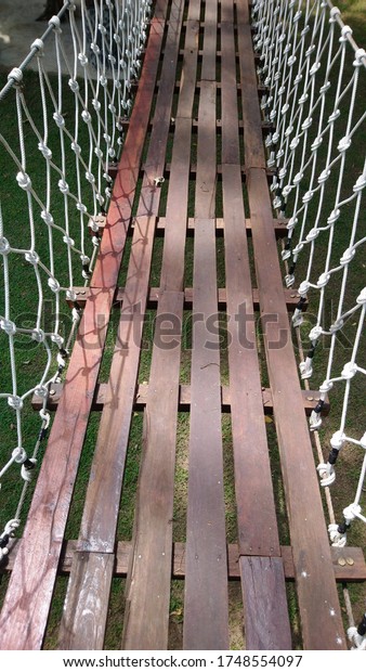 Suspension Bridge In the garden, the bridge floor
is made of brown wood, fastened with nails. There is a white rope
knitted into a mesh on the side. Hang next to two trees to use as a
connecting walkway