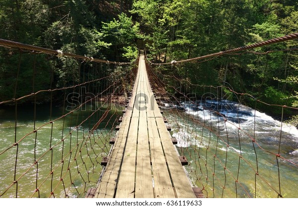 Suspension bridge over Cane Creek at Fall Creek\
Falls State Park in Tennessee gives beautiful overlook to waterfall\
underneath & it connects a hiking trail that leads to other\
waterfalls in the\
park.