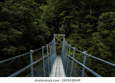 A suspension bridge spanning over a forest river, blending modern engineering with natural surroundings.