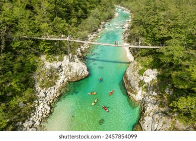 A suspension bridge spans the emerald waters of the Soca River in Slovenia, aerial view. This spot is a favored destination for kayaking and trekking in Slovenia. - Powered by Shutterstock