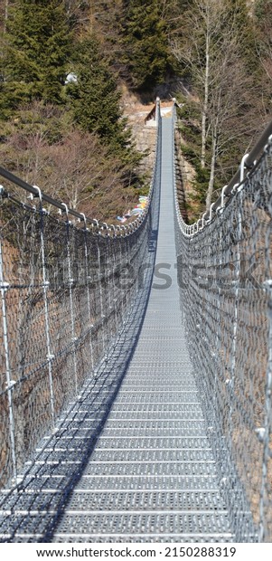 suspension bridge in the void at high\
altitude in the mountains supported by sturdy steel\
ropes