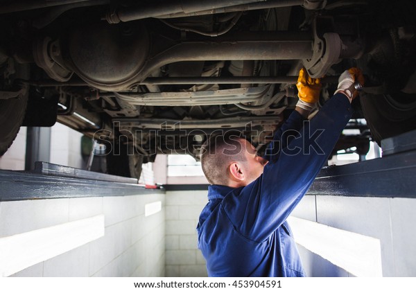 Suspension system of SUV restoration in\
garage. Mechanic recovering car wheel under\
vehicle