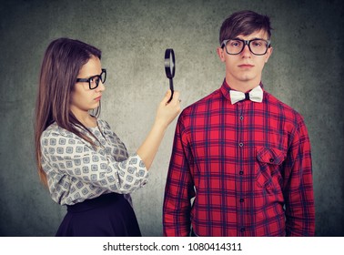 Suspicious and attentive girl selecting man while exploring him through magnifying glass in details.  - Powered by Shutterstock