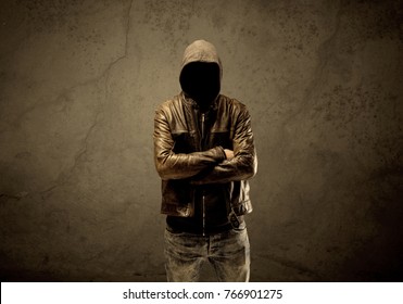 A suspicious faceless mature male in dark urban environment and light in front of a concrete empty wall background