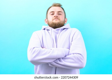 A Suspicious Man With Crossed Arms Looks From The Top On A Blue Background. Person. Standing. Man. Portrait. Adult. Arm. Crossed. Male. Happy. Studio. Confidence. Confident. Guy. Smile