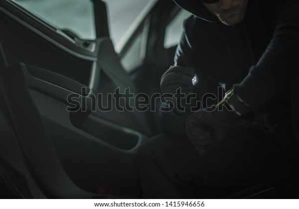 Suspicious Men with Small Flashlight in a\
Car. Vehicle Theft or Robbery Concept\
Photo.