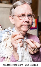 Suspicious Old Woman In Pink Sweater Crocheting At Home