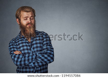 Suspicious skeptical man looking to the side to copyspace. Hipster male with beard in blue plaid checkered shirt  Isolated on gray grey studio Background. Negative face expression, human emotion, body