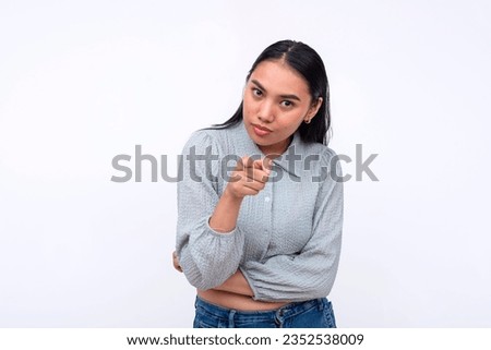 A suspicious young asian woman making an accusation. Pointing to the camera, blaming someone. Isolated on a white background.