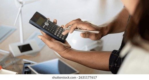Sustainability and Engineering. Engineer using calculator for sustainable project analysis.