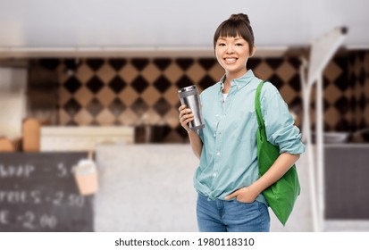 sustainability and people concept - asian woman with thermo cup for hot drinks and green reusable bag for food shopping over food truck background - Powered by Shutterstock