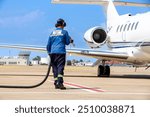 Sustainable Aviation Fuel (SAF). Technician refueling private jet with SAF at the airport.