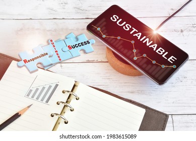 Sustainable Business And Finance Technology On Smart Phone Screen With Growth Graph On Wireless Charger With Responsible Business Success Written On Blue Puzzle On Desk. Sustainability Solution Idea