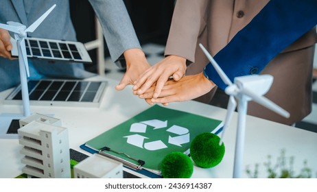 Sustainable business meetings at desks, green energy concepts. People in business suits discussing eco-friendly solutions, solar cells, wind turbines, and promoting net-zero practices. - Powered by Shutterstock