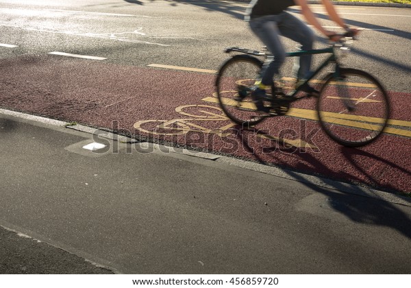 Sustainable city transportation: Bikers commuting\
to the work, riding fast in a cycling line on the street (motion\
blurred image)