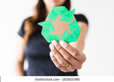 sustainable development concept, woman holding a recycle sign towards the camera shot at shallow depth of field